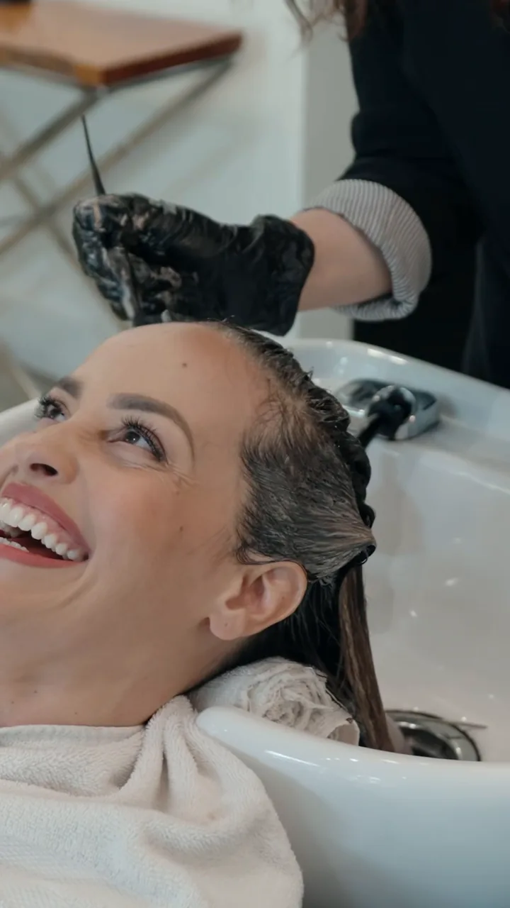 A toner formula on the studio iPad, then gloss applied at the wash bowl to a laughing client.