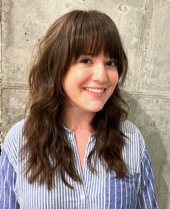 Long brunette layers with a full fringe and relaxed lived-in waves.