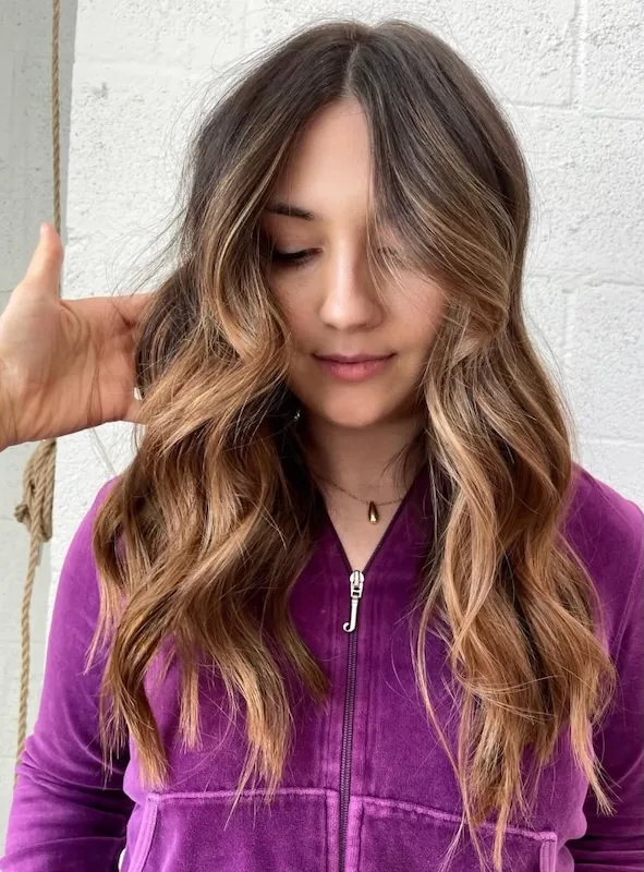 Caramel balayage hand-painted through dark brunette lengths, with a golden money piece.