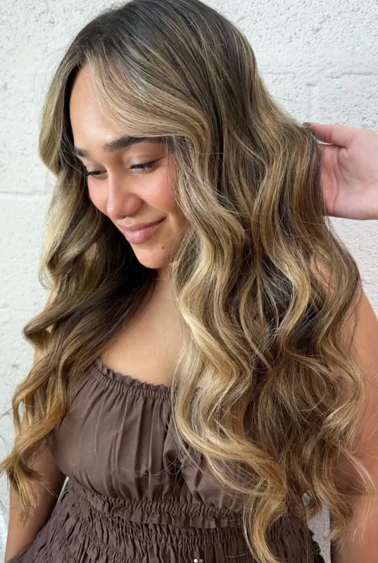 Caramel-bronde balayage in long glossy defined waves.