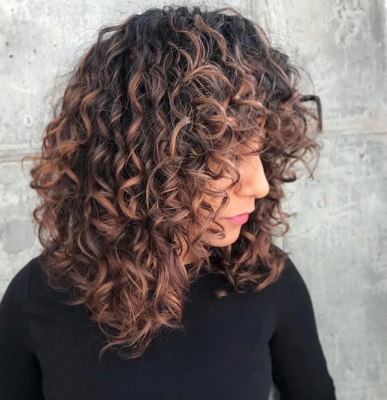 Copper-lit dark curls cut into a curly lob.