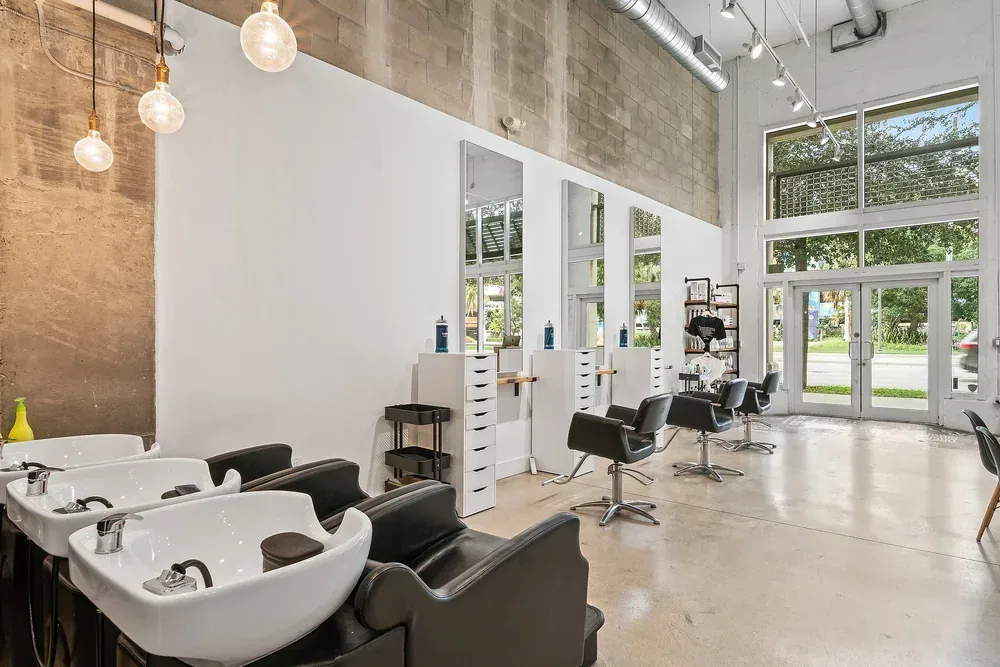 The shampoo area of the West Palm Beach hair salon: black basins under bare pendant bulbs.